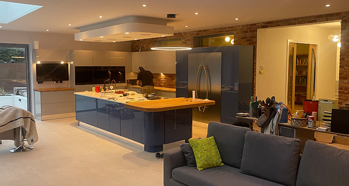 modern kitchen renovation featuring blue cabinets and wooden countertops with seating area and open layout